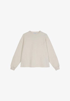 Sudadera beige, corte holgado, cuello redondo, mangas largas con puños acanalados, el lado izquierdo del pecho presenta un sutil bordado floral. Textura suave.