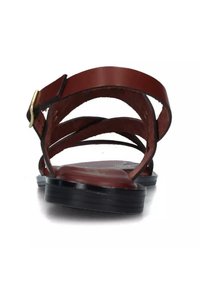 Sandalo in pelle marrone con cinturini incrociati e una fibbia dorata. Suola nera piatta con leggera texture, vista da dietro.