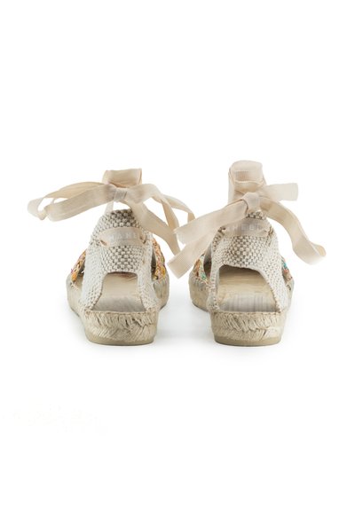 Sandali espadrille intrecciati con tonalità marrone chiaro, design aperto sul retro, decorazioni floreali e nastri beige per la chiusura.