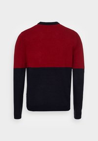 Jersey color bloqueado en rojo y azul marino con cuello redondo, puños acanalados y una textura de punto suave, diseñado para la comodidad y el calor.