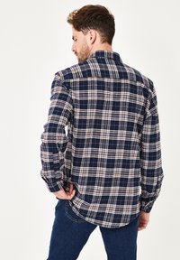 Navy-kariertes Hemd aus Flanell, mit weißen und beigen Linien, einem Button-Down-Kragen und langen Ärmeln mit knöpfbaren Manschetten.