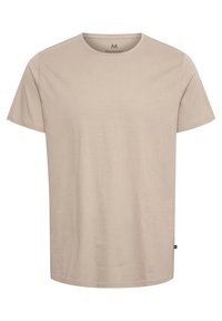 Beige színű, rövid ujjú póló, puha pamutból készült. Kerek nyakkivágással és egy kis logós címkével rendelkezik a bal oldalon. Simaság jellemzi.