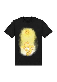 Černé bavlněné tričko s potiskem karikatury medvěda se slunečním motivem, podrobným v žluté a bílé, na texturovaném světlem pozadí.