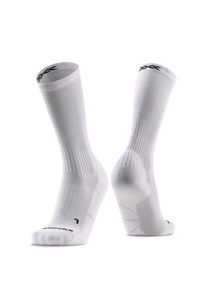 Een paar witte sportsokken met ribbelstructuur en een zwart logo bij de boord en de teen, rechtop geplaatst op een witte achtergrond.