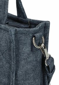 Granatowa torba z denimu o pikowanej fakturze, z metalową klamrą w kolorze srebrnym i dwoma mocnymi uchwytami. Prostokątny kształt z wzmocnionymi szwami.