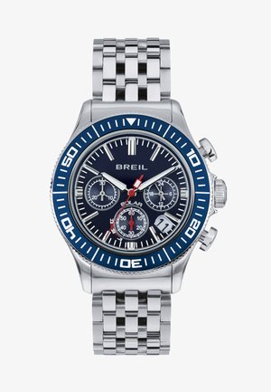 Kronografur med et hus og armbånd i rustfrit stål. Blå bezel, marineblå urskive, tre subskiver og røde accenter på visere og markører.