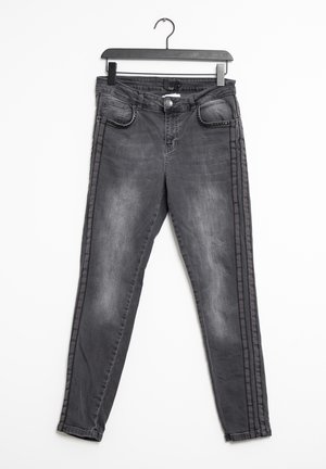 Jean en denim gris à coupe ajustée, présentant une légère décoloration, deux poches avant et des accents latéraux à rayures contrastées.