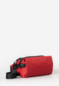 Borsa impermeabile rossa con cerniera nera e tracolla, caratterizzata da un design ripiegabile e regolazioni laterali per una vestibilità personalizzata.