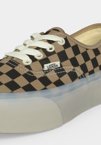 Κλασικό παπούτσι Vans με καφέ και μαύρο καρό σχέδιο, λευκά κορδόνια, λευκή ραφή και χοντρή λευκή λαστιχένια σόλα.