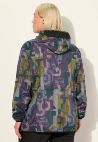 Färgglad huva jacka med ett geometriskt mönster i lila, grönt och blått, tillverkad av lätt material med elastiska manschetter.