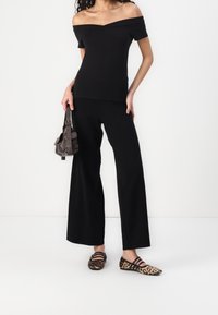 Černý top bez ramínek spárovaný s černými širokými kalhotami. Doplněno hnědou kabelkou a balerínami s leopardím potiskem. Celkově hladká textura.