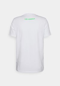 Camiseta de manga corta blanca con un logo verde de "KARL LAGERFELD" en la parte posterior, fabricada en tejido de algodón. Diseño simple y clásico.