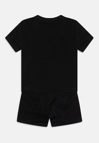 Camiseta negra de manga corta con cuello redondo y pantalones cortos negros a juego. Tela suave con un diseño simple y sin patrones ni gráficos visibles.