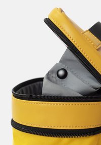 Borsa cilindrica gialla con cerniera nera e cuciture, che mostra un rivestimento interno grigio in vista, con un dettaglio di chiusura a scatto.