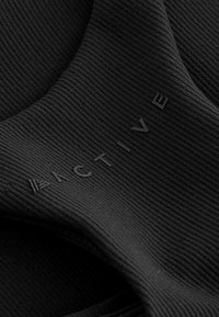 Sort aktivt stof med en ribbet tekstur, der prydes af det prægede ord "ACTIVE" i store bogstaver. Enkelt og glat design.