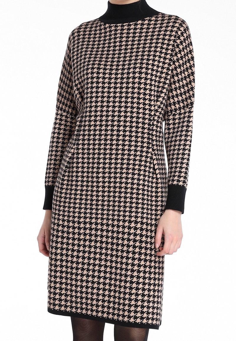 Robe tricotée avec un motif pied-de-poule en noir et beige, col montant, manches longues et poignets côtelés. Texture lisse.
