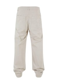 Pantalons beige clair à coupe décontractée, avec une texture lisse, des poignets élastiques et deux poches arrière. Design simple sans motifs.