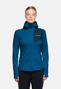 Giacca in pile blu con cappuccio, tasche con zip, pannello centrale nero e fori per i pollici nei polsi. Tessuto liscio con elementi di design minimi.