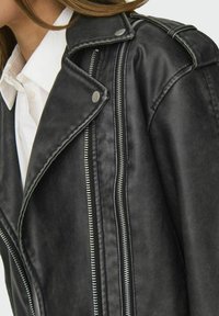 Czarna kurtka motocyklowa z syntetycznej skóry z srebrnymi zamkami błyskawicznymi. Posiada napy przy kołnierzu, szczegółowe przeszycia i teksturowane wykończenie.