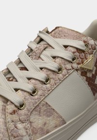Baskets avec motif beige en peau de serpent, panneau en cuir beige clair, lacets épais beige et œillets dorés ainsi que détail triangulaire.