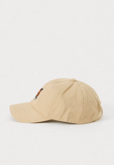 Beige színű baseball sapka ívelt karimával, melynek elülső paneljén egy kicsi hímzett róka fej található, oldalnézetből látható.