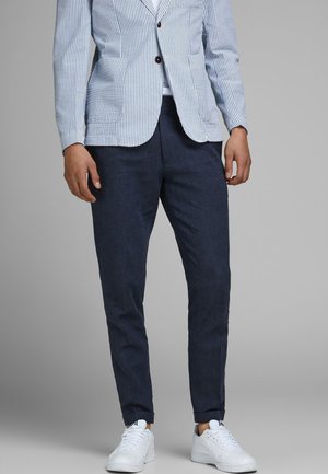 Navyblauwe op maat gemaakte broek van geweven stof, met een slim fit en omslagboorden, gecombineerd met witte sneakers en een gestreepte blazer.