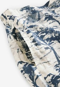 Stof med et blå og cremefarvet botanisk print, der har en blød tekstur og en plisseret design. Inkluderer en elastisk talje for fleksibilitet.