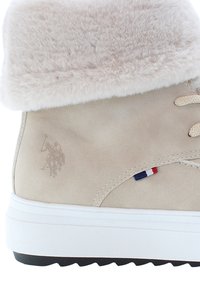 Beige mockasinfot med en mjuk, ljus creamfärgad faux fur krage. Har en diskret polo-logotyp och en trefärgad detalj nära snörningen.
