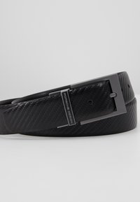 Ceinture noire avec une surface texturée, présentant une boucle métallique rectangulaire de teinte sombre, gravée "Porsche Design".
