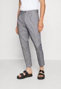 Gray textured trousers with a tailored fit, featuring a button closure, side pockets, and cropped ankle length, paired with black sandals.