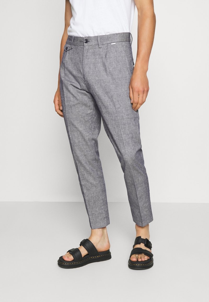 Gray textured trousers with a tailored fit, featuring a button closure, side pockets, and cropped ankle length, paired with black sandals.