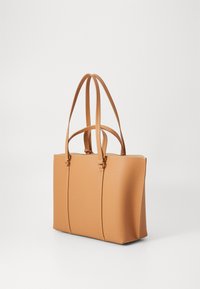 Karameles krāsas ādas somiņa ar divām garām siksnām, gluda tekstūra, strukturēta forma, zelta krāsas aparatūras akcenti un šuvuma detaļas.