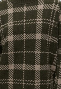 Motif à carreaux vert foncé et beige sur un tissu tricoté doux avec des lignes diagonales et droites formant des carrés.