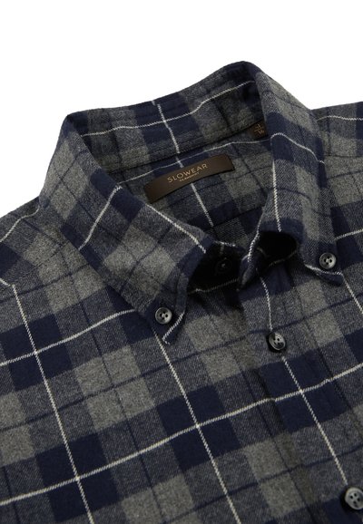 Camisa de cuadros en tonos azul marino y gris, confeccionada en suave franela, con cuello abotonado, botones negros y una textura cómoda.