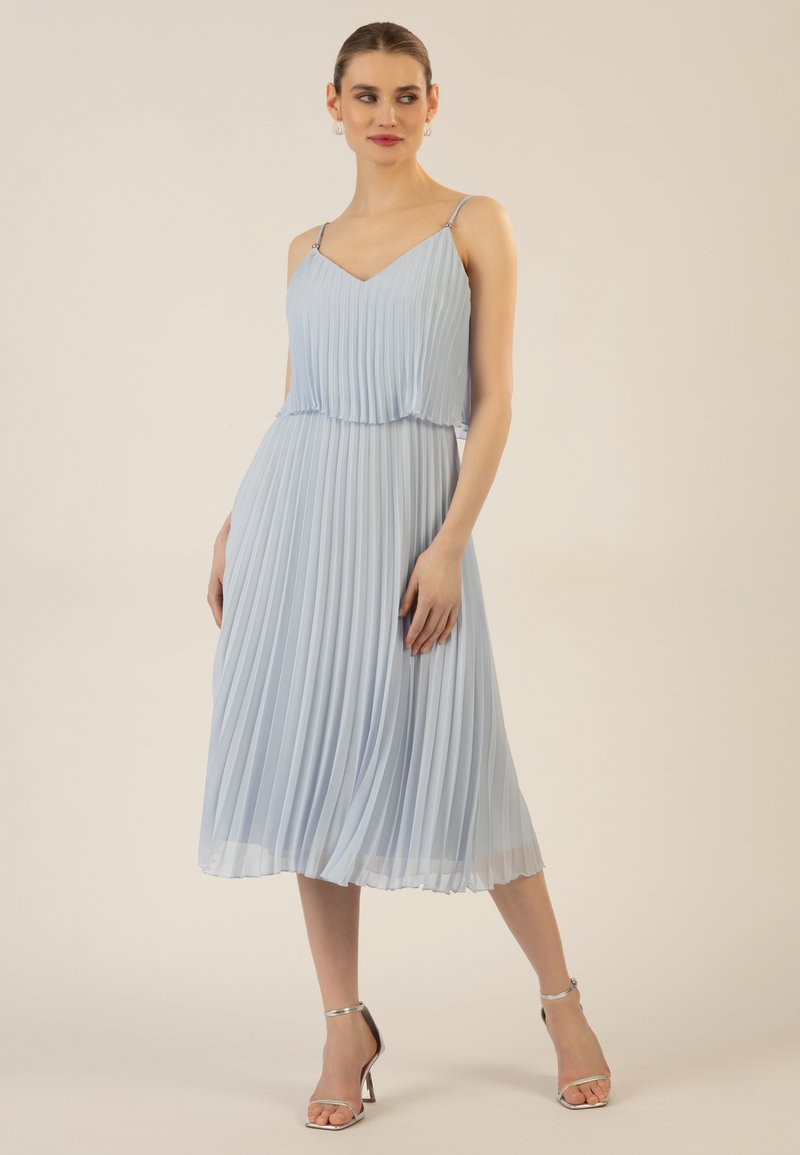 Hellblaumes, plissiertes Kleid mit Spaghetti-Trägern und V-Ausschnitt. Glatter Stoff, mittellang, sanfter Fall mit A-Linien-Silhouette. Silbergraue Absatzsandalen.