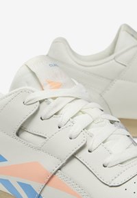 Sneakers bianchi in pelle con accenti azzurri e pesca, con lacci piatti e un tallone testurizzato. Marchio visibile sulla linguetta.