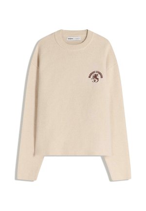 Beige neulepusero pyöreällä kaula-aukolla ja pitkillä hihoilla; etuosassa ruskealla painettu logo, pehmeä tekstuuri ja rento muotoilu.