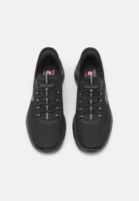 Black mesh athletic shoes with a rounded toe, elastic laces, and a padded collar. Features a Skechers logo on the side and a flexible outsole.