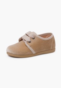 Scarpa in velluto beige con punta arrotondata e cinturino elastico, superficie testurizzata, suola in gomma e dettagli di cucitura minimal lungo i bordi.