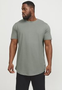 Short-sleeve t-shirt in olive green, round neckline, relaxed fit, made of smooth fabric; features a rounded hem and minimal branding detail.