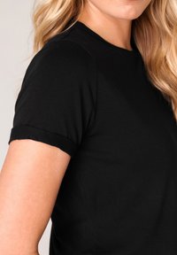 Schwarzes T-Shirt mit kurzen Ärmeln, Rundhalsausschnitt und leicht umgeschlagenen Bündchen, gefertigt aus weichem, glattem Stoff mit taillierter Passform.