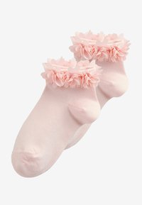 Par lyserøde babystrømper med flæsekant og bløde stofblomsterapplikationer omkring anklerne.