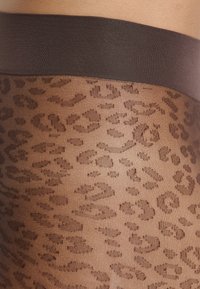 Collant a fantasia leopardata marrone con una vita in tinta unita marrone scuro. La texture è trasparente e liscia, con un motivo animale ripetuto.