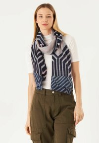 Écharpe multicolore avec des motifs géométriques en bleu marine, bleu clair et rose, fabriquée dans un tissu doux et texturé avec des bords effilochés.
