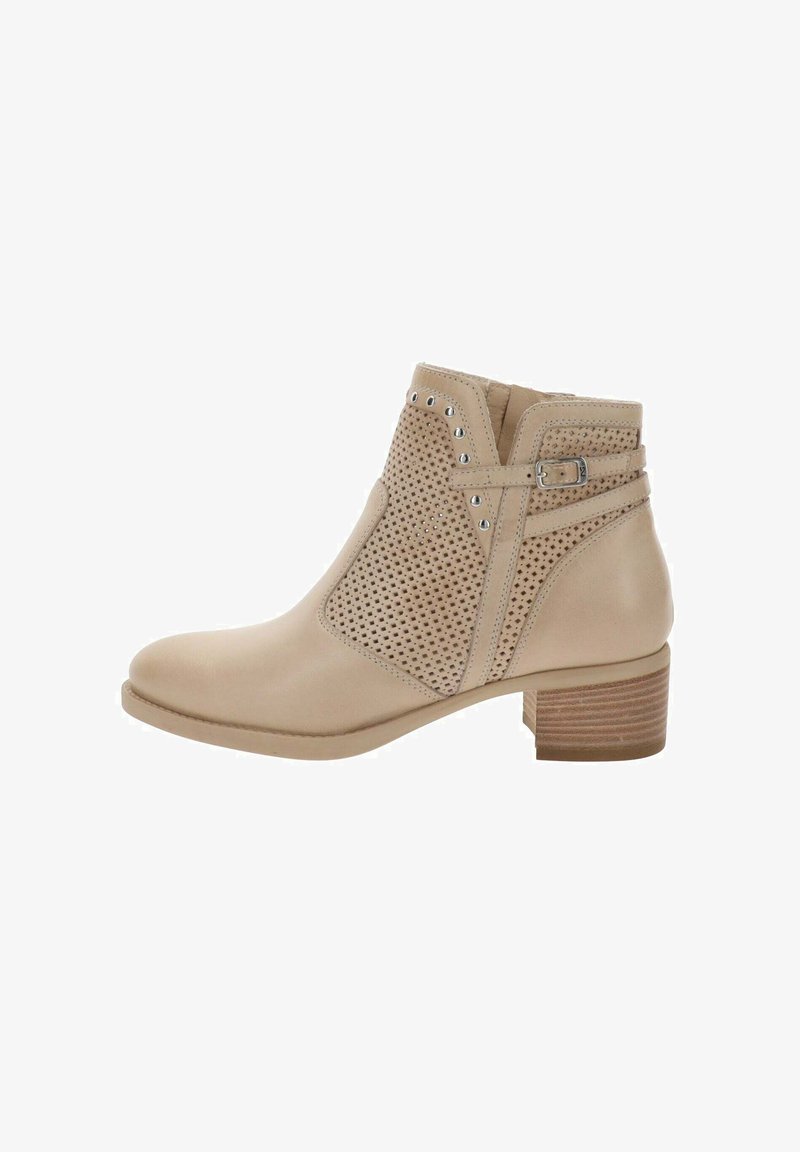 Bota beige hasta el tobillo con laterales perforados, tachuelas plateadas, una correa decorativa con hebilla y un tacón bajo apilado de madera.