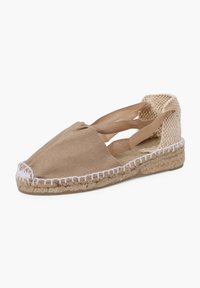 Espadrillas in tela color sabbia con suola in juta texture, cuciture bianche lungo il bordo e design con cinturino incrociato alla caviglia.