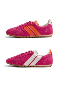 Deux baskets en daim rose avec des semelles couleur sable, l'une avec des rayures orange et l'autre avec des rayures blanches, présentées en profil sur fond blanc.