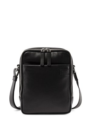 Black square leather crossbody bag with front pocket, dual zipper closure, and adjustable shoulder strap on white background.