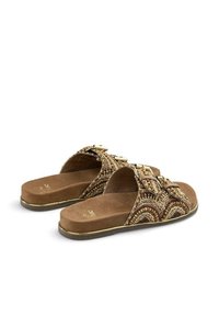 Flache Sandalen aus einem braunen Wildleder ähnlichen Material, verziert mit einer Perlenschnur in Wellenmuster, mit goldenen Akzenten und einer gepolsterten Sohle.