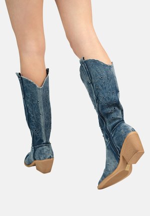 Botas de vaquero hasta la rodilla de mezclilla con punta afilada, color azul deslavado, bordado floral y tacón de bloque texturizado en color marrón claro.